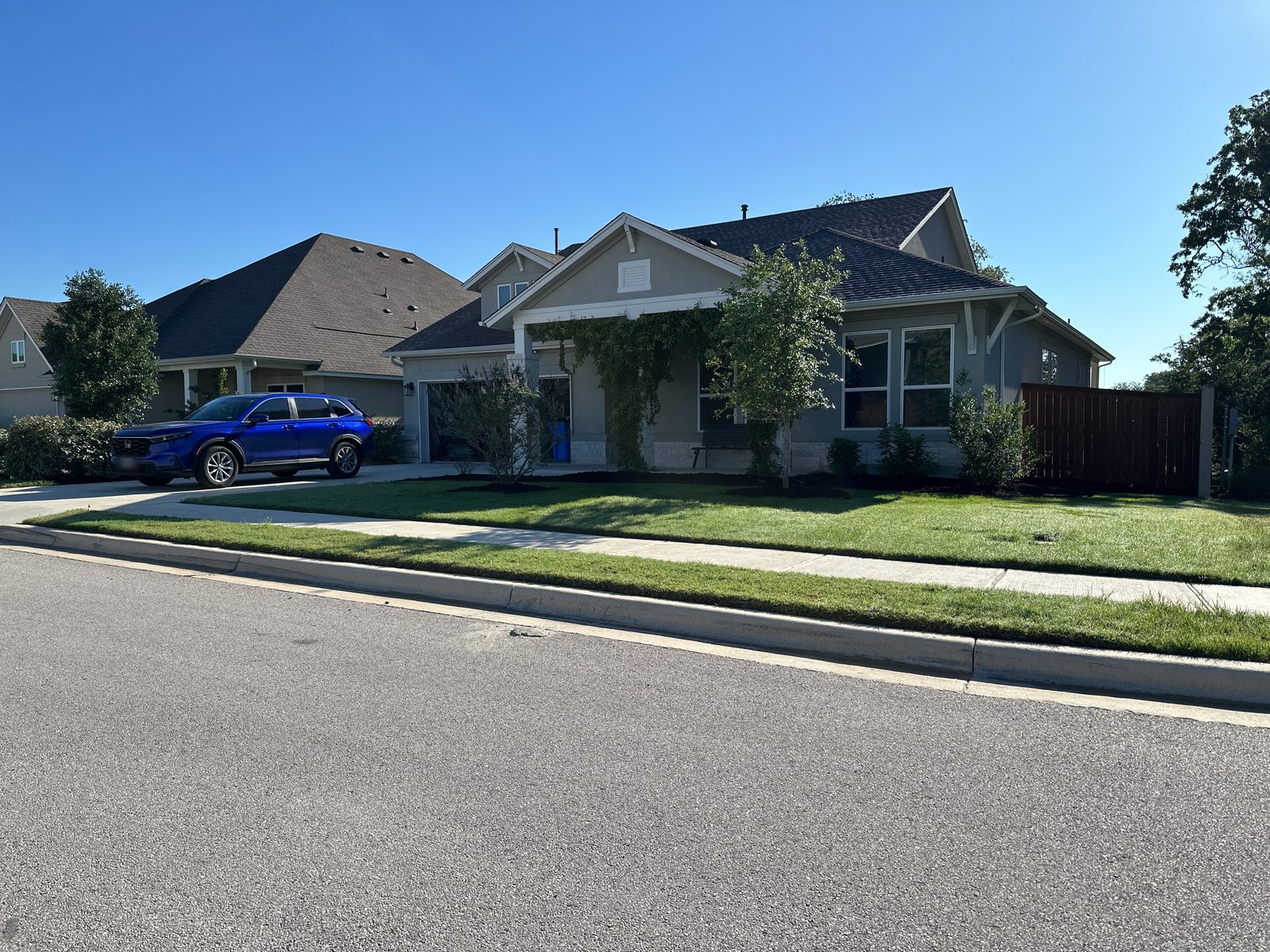 Ernie's house, seen from the street on a clear day, with a blue SUV parked in the driveway.