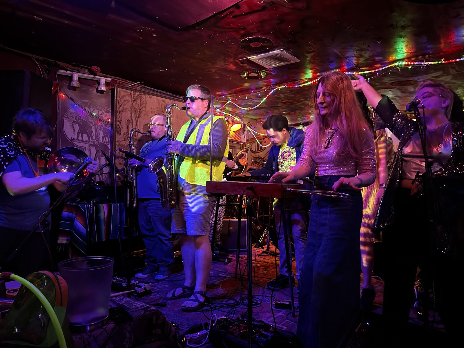 Ouiness at a bar under fairy lights, this line-up carrying two saxophones.