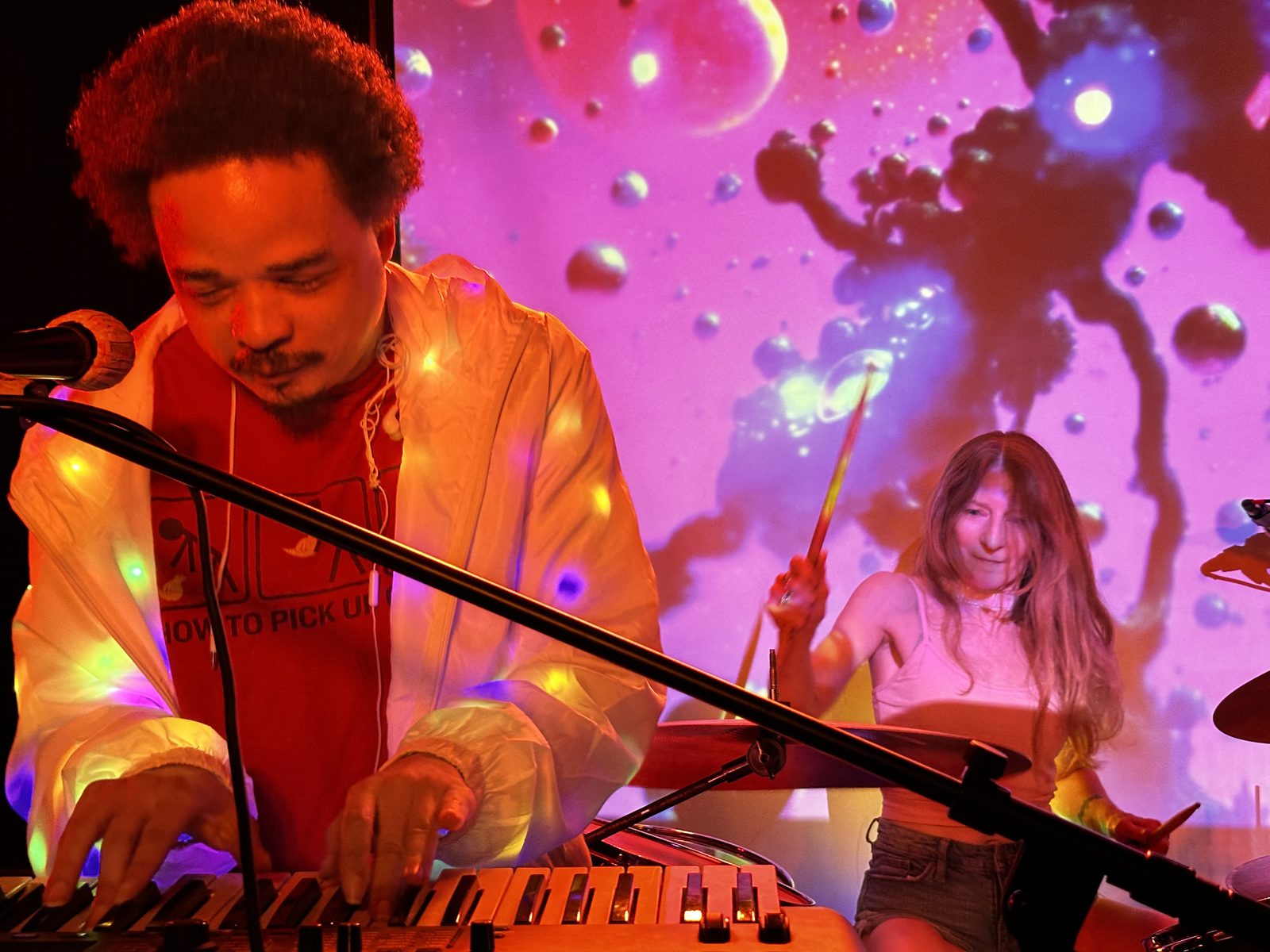 T.J. Wade and Anne Heller of jazz funk band Line of Fire, T.J. in a light-up jacket under a liquid light show.