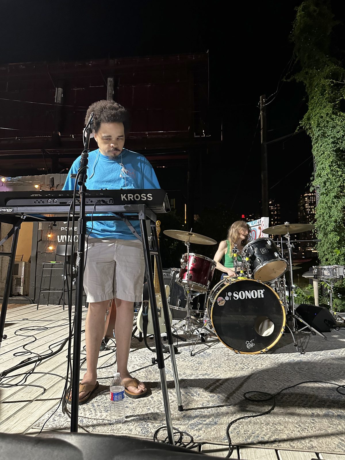 T.J. Wade on keys and Anne on drums, Line of Fire playing an outdoor stage in Austin at night.