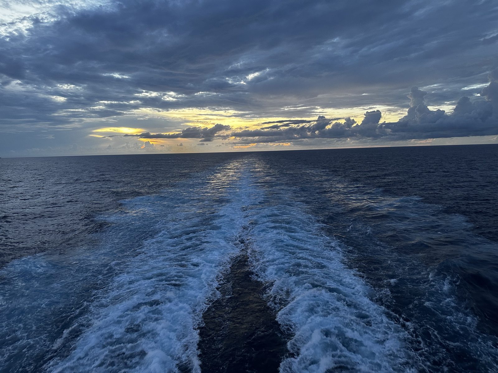 Sunset over the ship's wake in open water.