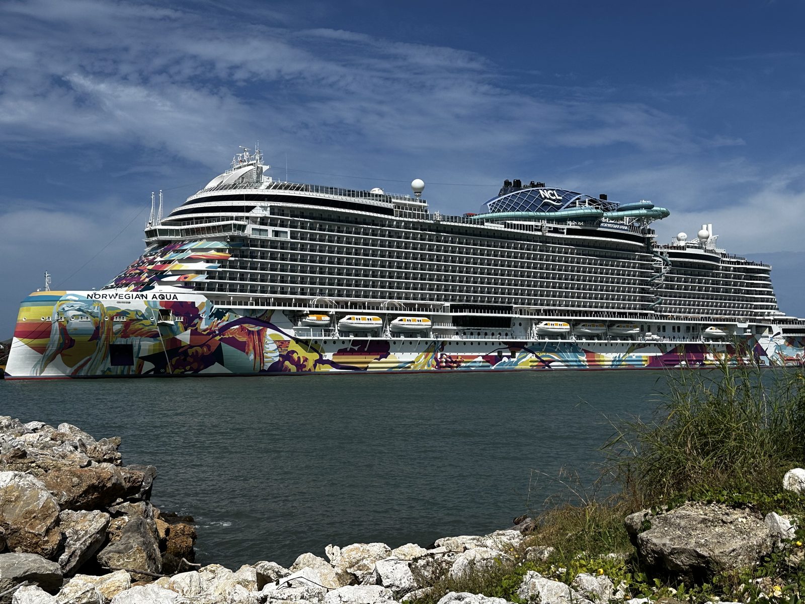 The Norwegian Aqua in full profile at Puerto Plata, seen across the rocks.